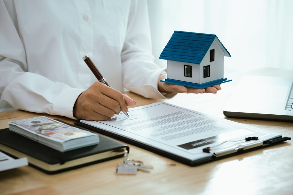 Real estate agents present home designs and discuss documents that reflect real estate investing, property purchases, mortgage planning, home loans, financial advice, and safe housing decisions.