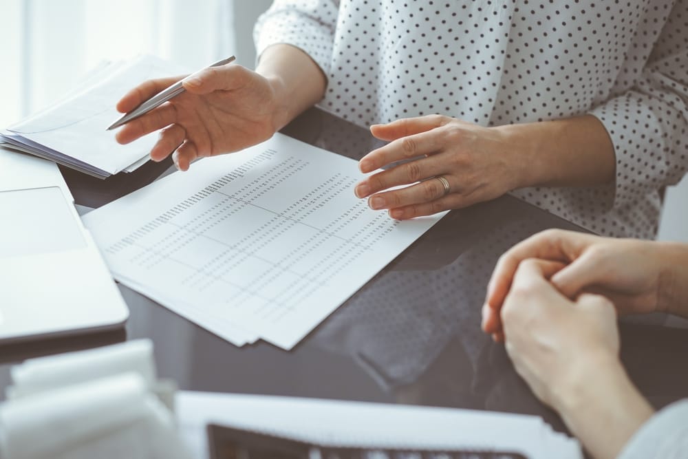 Woman accountant using a calculator and laptop computer while counting taxes for a client. Business audit and finance concepts